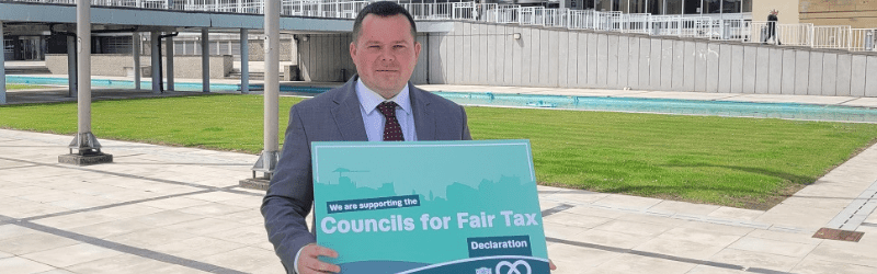 Councillor Joe Fagan holding Councils for Fair Tax foam board