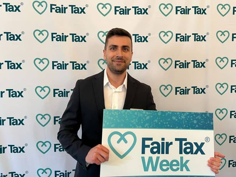 man holding Fair Tax Week photo prop in front of Fair Tax branded background