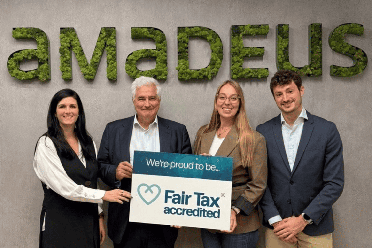 Amadeus team holding sign saying 'We are proud to be Fair Tax accredited'